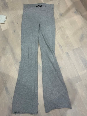 Grå bootcut mjukisbyxor 157 XS - Grå mjukisbyxor från 157 i storlek XS. Byxorna har bootcut-modell med utsvängda ben och hög midja. Tillverkade i mjukt bomullsmaterial och har en enkel dragsko i midjan. Perfekta för en chill och avslappnad stil.