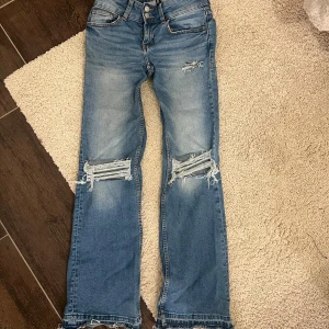 Blå slitna jeans från H&M Divided - Säljer ett par blå jeans från H&M Divided med slitningar och hål på knäna.