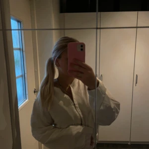 Vit kofta från 157, storlek S - Säljer en stilren vit kofta  från 157 i storlek S. Koftan har dragkedja framtill, ribbade muddar och klassisk bomberkrage. Perfekt för dig som gillar en clean och enkel look. Materialet känns lätt och passar bra till lager-på-lager.