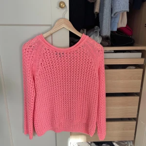 Rosa stickad tröja med hålmönster - Säljer en snygg rosa stickad tröja med hålmönster och rund hals. Tröjan har lång ärm och är perfekt för lager-på-lager. Den är lätt och luftig, vilket gör den grym till både vår och sommar. Enkel att styla med jeans eller kjol!