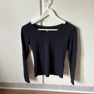 Svart långärmad topp från lager 157 - En basic svart långärmad topp från 157 i mjuk bomullsblandning med stretch. Enkel och stilren design med rund halsringning, perfekt att matcha med jeans eller kjol. Materialet är 95% bomull och 5% elastan för en skön passform.