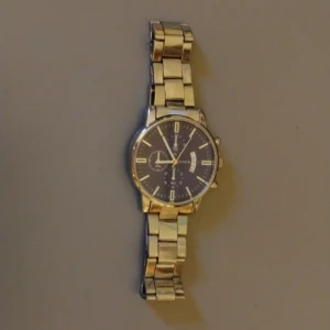 Silverfärgad klocka från Geneva - Stilren klocka med rund urtavla i svart och silverfärgade detaljer. Armbandet är i metall med breda länkar och har en klassisk design. Urtavlan har datumvisning och flera små visare för extra funktioner. Perfekt för dig som gillar en clean look. Klockan fungerar inte utan är som en fin accessoar, där av priset! Köpt på Aliexpress om jag minns rätt. Jag vet inte vad det är för märke det var Plick som valde det!