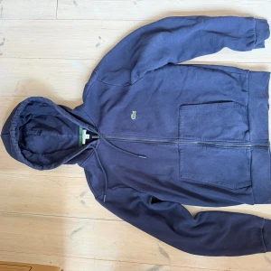 Lacoste hoodie - Den är mer mörkblå än den verkar i bilderna. Längst ned på dragkedjan finn det spår av användning annars fint skick
