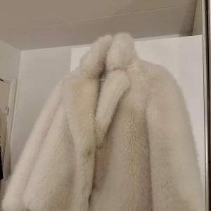 Vit fluffig pälsjacka med krage - Supermjuk och oversized vit pälsjacka med bred krage och klassisk siluett. Jackan har en lyxig känsla och är perfekt för dig som vill sticka ut med en riktigt statement piece. Passar dig som gillar att hålla värmen och ändå se riktigt stylish ut. Ifrån Zara och helt oanvänd 