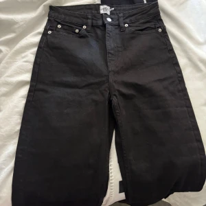 Svarta jeans straight fit - Svarta Levis 501 jeans med klassisk rak passform och fem fickor. Hög midja och silverfärgade nitar. Tidlös modell i jeansmaterial som funkar till allt. Snygga bakfickor och knappgylf. Perfekta svarta jeans för dig som gillar enkel och clean stil.