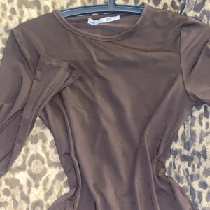 Brun långärmad tröja från 157 - Säljer en enkel och stilren brun långärmad tröja från 157. Tröjan har rund halsringning och är gjord i ett mjukt, stretchigt material som sitter snyggt på kroppen. Perfekt att matcha med jeans eller kjol för en clean look.