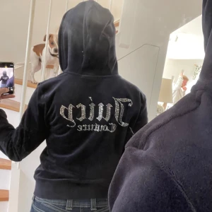 Juicy Couture blå velour hoodie - Svart hoodie från Juicy Couture i mjuk velour med glittrande strasstext på ryggen. Tröjan har huva, dragkedja framtill och fickor. 