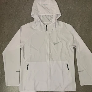 Vit Nike Miller vindjacka  - Nike Miller vit löparjacka Säljer min Nike Miller vit löparjacka. Lätt och bekväm, perfekt för höst och vår. Bra för löpning och fotboll. Endast använd en gång. 