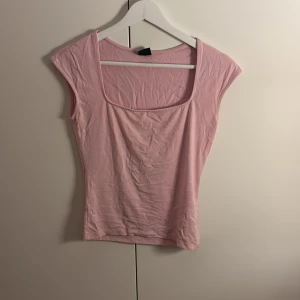 Ljusrosa topp från Gina Tricot - Säljer en ljusrosa topp från Gina Tricot med fyrkantig ringning och ärmlös design. Tight passform och knappt använd. 