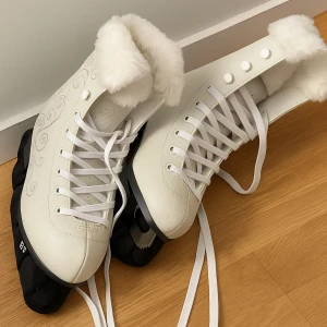 Vita skridskor med fuskpäls - Snygga vita skridskor med fluffig fuskpäls runt skaftet och vita snören. Skorna har dekorativa mönster på sidorna och en klassisk form med rund tå. Perfekta för vinterns isbanor och ger en riktigt mysig vibe.