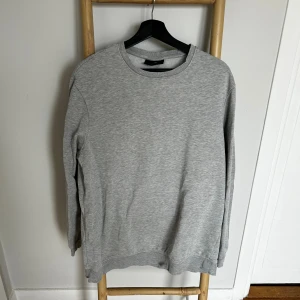 Grå sweatshirt från H&M, relaxed fit - Enkel och stilren grå sweatshirt från H&M i relaxed fit. Tröjan har rund halsringning, långa ärmar och ribbade muddar vid ärmslut och nederkant. Perfekt för en chill och avslappnad look.