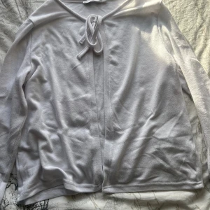 Vit kofta med knyt från lager 157 i storlek 160 - Vit kofta från 157 med långa ärmar och snygg knytning framtill vid halsen. Enkel och stilren design i mjukt bomullsmaterial, perfekt att slänga över en topp. Passar dig som gillar en clean och chill look. Använd en gång förut och i helt nytt skick.