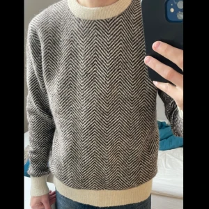 Randig stickad tröja från Selected Homme - Säljer en stickad tröja från Selected Homme i svart och beige med snyggt fiskbensmönster. 