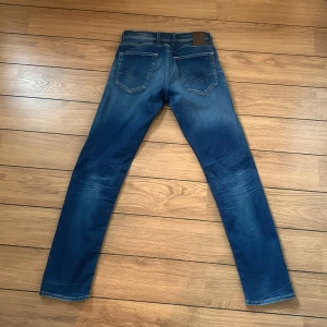Replay Grover jeans blå, midwaist - Snygga Replay Grover jeans i klassisk blå tvätt med lätt slitning och raka ben. Jeansen har fem fickor, normal passform och är tillverkade i slitstarkt bomullsmaterial. Perfekta för dig som gillar en tidlös och stilren look.