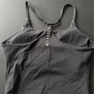 Svart linnetopp från Relode - Snygg svart linnetopp från Relode med tunna axelband och logga framtill. Perfekt för träning eller en sportig look. Toppens material är stretchigt och följsamt för maximal komfort.