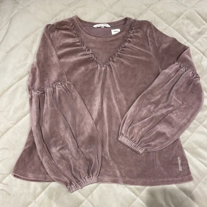 Lila sammetströja | Odd Molly - Superfin lila tröja från Odd Molly i mjuk sammet. Tröjan har långa puffärmar med resår och volangdetaljer vid axlar och ärmslut. Broderad Odd Molly-logga nertill. Meddela gärna vid frågor 💜