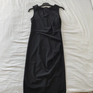 Svart ärmlös långklänning  - Elegant svart klänning i figurnära modell. Perfekt till fest, middagar eller andra speciella tillfällen. Klassisk design som aldrig går ur tiden och lätt att styla med smycken eller en kavaj. Använd få gånger och i fint skick.