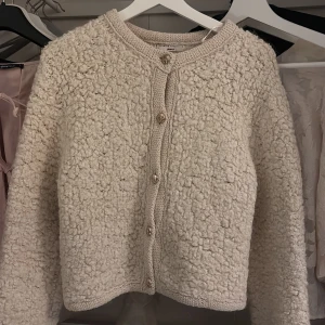 Beige kofta  - Mysig beige kofta från Gina Tricot i ett fluffigt material. Koftan har långa ärmar och knäpps med knappar framtill. Inte använd mycket men knappen längst ner har ramlat av!