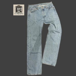 Levi's 501 ljusblå jeans straight fit - Klassiska Levi's 501 jeans i ljusblå denim med rak passform. Byxorna har fem fickor, knappgylf och den ikoniska läderpatchen bak i midjan. Perfekta för en avslappnad och tidlös look. Tillverkade i slitstarkt bomullsjeans.