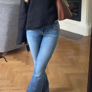 Bootcut jeans i ljusblå denim - Snygga ljusblå bootcut jeans med  orange sömmar och coola bakfickor. Dom är lågmidjade och i fint skick. Strl 25:32