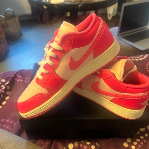 Nike Jordan 1 Low rosa/vit EUR 39 - Nike Jordan 1 Low sneakers i en snygg rosa och vit färgkombo. Skorna har klassisk snörning, rund tå och platt sula. Endast testade ej utomhus pris går att  diskutera vid snabb affär, nypris 1500