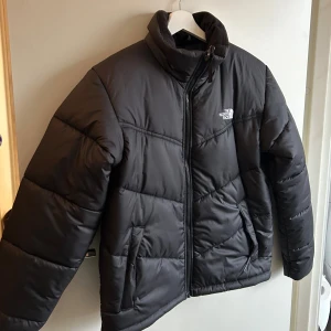 Svart pufferjacka The North Face - Säljer en svart pufferjacka från The North Face. endast använd fåtal 3-4 gånger då jag har haft det som en ”när det är som kallast jacka”. Köpt för 1526 kr på rea, original pris 2500 när jag köpte den. Skriv i dm om ni vill diskutera pris. Jackan har quiltad design, dragkedja framtill och två sidofickor. ”Modellen” är man/unisex men jag är kvinna och har använt den och den passar utmärkt. Det är storlek S.