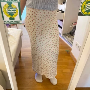 Vit blommig långkjol med slits - Supersöt långkjol i vit med små blommor i rosa och orange. Är osäker på storlek men skulle gissa på XS/S. Även okänt märke