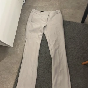 Beiga kostymbyxor från BikBok - Snygga beiga kostymbyxor från BikBok som är bootcut med hällor för bälte och diskreta bakfickor i strl 36. Perfekt passform och stilren look som passar till många olika outfits. Använda 1-2 ggr. Säljer då dom inte används💞