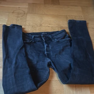 Mörkblå tapered jeans Jack & Jones - Snygga mörkblå jeans från Jack & Jones, modell Tapered/Mike. Jeansen har klassisk femficksdesign, normalhög midja och avsmalnande ben. Tillverkade i bomullsmix med stretch för extra komfort. Perfekta för en avslappnad och trendig look.