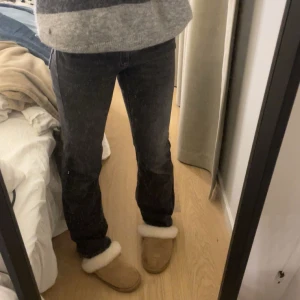 Svarta bootcut jeans med låg midja - Säljer ett par svarta jeans med bootcut-snitt och låg midja. Jeansen har klassiska fem fickor, silverfärgade knappar och dragkedja. Materialet är jeans med en lätt stretch och de har en snygg, mörk tvätt. Perfekta för dig som gillar en tidlös och avslappnad stil.