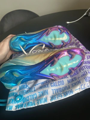 Nike mercurial Vapor 16 elite - Säljer ett par Nike Zoom fotbollsskor med beige stickad ovandel och snörning. Sulan har en cool mix av blått, lila och turkost med Nike-logga. Skorna har rund tå och platt sula, perfekt för dig som vill ha snygga och lätta skor på planen. Original skopåse medföljer.