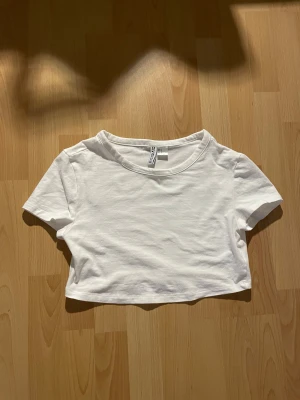 Vit croppad t-shirt - Vit croppad t-shirt. T-shirten har rund halsringning och korta ärmar.