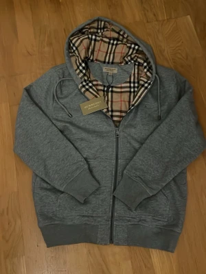 Burberry zip hoodie  - En riktigt snygg zip hoodie från burberry, den har en snygg logga på bröstet och burberry mönster inuti tröjan, den har inga defekter och är skön o varm, pris kan diskuteras.