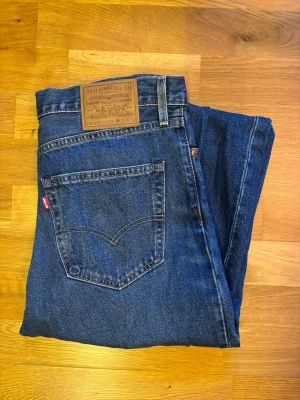 Levi's Lot Stay Loose jeans 568 blå W30/L32  - Säljer ett par Levi's Stay Loose jeans i klassisk blå denim. Modellen har raka ben, normal passform och fem fickor. Jeansens midja är midwaist och materialet är slitstark bomull. Perfekt för dig som gillar en avslappnad stil och vill ha lite extra rörelsefrihet. OBS KNAPPT ANVÄNDA.