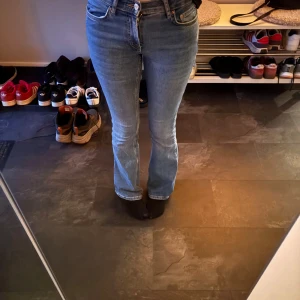Blå bootcut jeans från Gina Tricot - Säljer ett par ljusblå bootcut jeans från Gina Tricot, modell Perfect Jeans. De har medel hög midja och klassisk femficksdesign. Jeansen är i stretchigt denimtyg och sitter snyggt över höfterna innan de släpper ut vid bensluten.