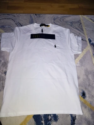 Vit t-shirt från Polo Ralph Lauren - Klassisk vit t-shirt från Polo Ralph Lauren med den ikoniska lilla loggan broderad på bröstet. T-shirten har rund halsringning och korta ärmar. Tillverkad i mjuk bomull för en skön känsla och clean look.