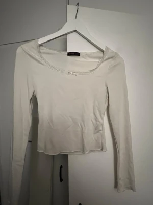 Vit långärmad blus med rosett - Säljer en söt vit långärmad blus med rundad halsringning och liten rosett framtill i storlek xs.💕