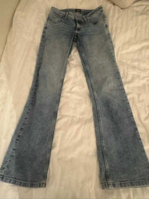 Ljusblå bootcut jeans från Lee - Säljer ett par ljusblå jeans från Lee med klassisk femficksdesign och bootcut-ben. Med låg midja Jeansen har normal passform och är tillverkade i mjukt denimtyg. Perfekta för dig som gillar retrovibbar och vill ha ett par riktigt snygga jeans.