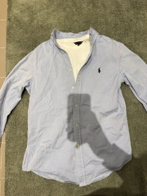 Ralph Lauren skjorta - Säljer en asfet ljusblå skjorta från Polo Ralph Lauren i toppskick utan defekter vad jag kan se.  Storlek 16 barn passar runt XS. 