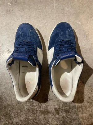 Valentino Rockrunner blå sneakers - Snygga Valentino Rockrunner sneakers i mörkblå mocka och vitt skinn. Klassisk låg modell med rund tå, snörning och vit platt sula. Perfekt för dig som gillar exklusiva streetwear-vibes och vill sticka ut med ett lyxigt märke. Kan ta emot byten👍Bra skick👌