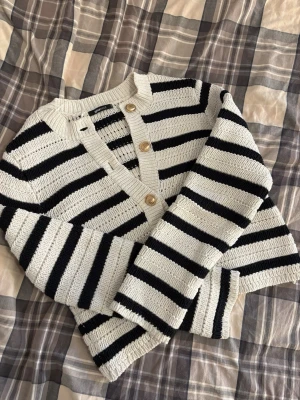 Randig kofta från Gina Tricot - Säljer en fin stickad kofta från Gina Tricot med svarta och vita ränder. Långärmad och i mjukt material.