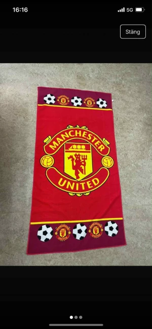 Ingen väst på bilderna - Bilderna visar en Manchester United-handduk med klubbens logga och fotbollsmotiv, men ingen väst finns med.