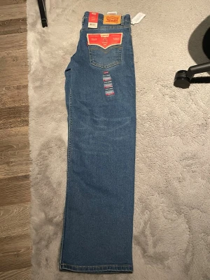 Levi's Stay Loose blå jeans - Säljer ett par Levi's Stay Loose jeans i klassisk blå färg. Modellen har en loose passform med raka ben och hög midja. Jeansen är tillverkade i stretchigt denim för extra komfort och har de ikoniska Levi's-detaljerna som bakficka med logotyp och etikett.