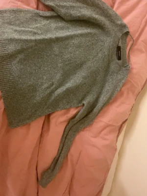 Grön /grå stickad tröja från Vero Moda - Mysig grå/grön  stickad tröja från Vero Moda med rund hals och ribbade muddar vid ärmslut och nederkant. Perfekt för kyliga dagar och enkel att matcha med jeans eller kjol. Långärmad och har en klassisk, normal passform.