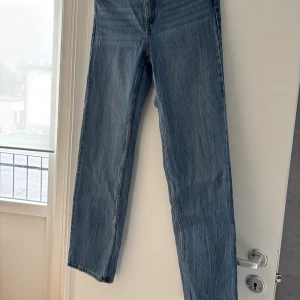 Blå raka jeans från Bershka - Säljer ett par klassiska blå jeans från Bershka med rak passform och hög midja. Jeansen har fem fickor, bälteshällor och rå kant nertill för en cool, avslappnad look. Tillverkade i bomullsdenim med en snygg tvättad finish. Storlek 36/38💕