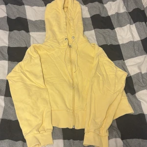 Gul hoodie med dragkedja från 157 - Gul hoodie från lager 157 i mjuk bomull med dragkedja framtill och snörning i huvan. Tröjan har långa ärmar, ribbade muddar och en skön, avslappnad passform. Perfekt för chill dagar eller när du vill ha något bekvämt och snyggt.