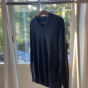 Mörkgrå stickad tröja Polo Ralph Lauren - Mörkgrå stickad tröja från Polo Ralph Lauren med v-ringning. Bra skick, perfekt inför hösten då den värmer bra. 
