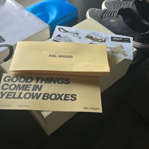 Svarta sneakers från Axel Arigato - Snygga svarta sneakers från Axel Arigato med ovandel i mocka och klassisk vit platt sula. Skorna har diskret guldfärgad logga på sidan och svarta snören. Perfekta för dig som gillar stilrena och trendiga skor med premiumkänsla. Köpt för 2999kr