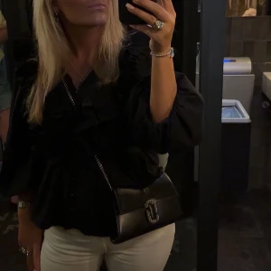 Handväska från Marc Jacobs - Snygg svart handväska från Marc Jacobs med silverfärgad kedja och dekorativt spänne framtill. Väskan är sparsamt använd och har inga defekter på! Jag har kvitto och lappen från Marc Jacobs sparat! Original pris 4800kr🩷säljer för 3300kr men vid snabb affär kan jag sälja billigare