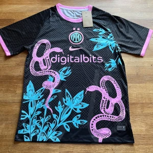 Inter Milan Fotbollströja - Inter Milan x Nike fotbollströja i svart med rosa och turkosa detaljer. Snyggt tryck med ormar och blad, rosa kant vid hals och ärmslut. Digitalbits-logga framtill. Tillverkad i lätt och ventilerande polyester, perfekt för match eller träning.
